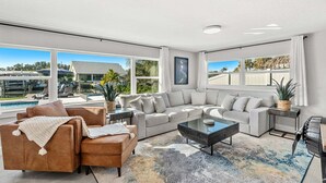 Un salon spacieux avec un grand canapé, une table basse et une vue sur une piscine et un espace extérieur.