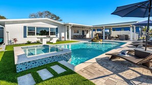 Une maison moderne dotée d’une piscine, de mobilier d’extérieur et d’un espace patio.