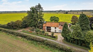 A rural house with a red-tiled roof, surrounded by fields and trees. - 4 Bed in Litcham (oc-h30106) (Litcham)