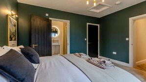A bedroom with a large bed, a bedside table, a mirror, and a wardrobe. - 4 Bed in West Runton (oc-c30082) (West Runton)