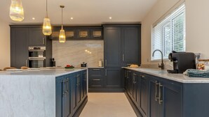 A modern kitchen with dark cabinetry, a marble countertop, and pendant lighting. - 4 Bed in West Runton (oc-c30082) (West Runton)