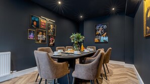 A modern dining area with a round table, six chairs, and a central vase. - 4 Bed in West Runton (oc-c30082) (West Runton)