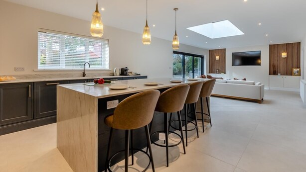 A modern kitchen with a central island, bar stools, and pendant lighting. - 4 Bed in West Runton (oc-c30082) (West Runton)