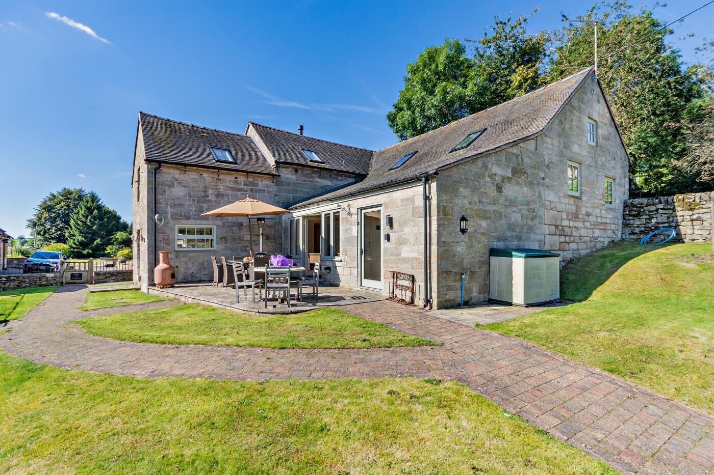 Une maison en pierre dotée d’une terrasse, d’un coin repas et d’un petit jardin.