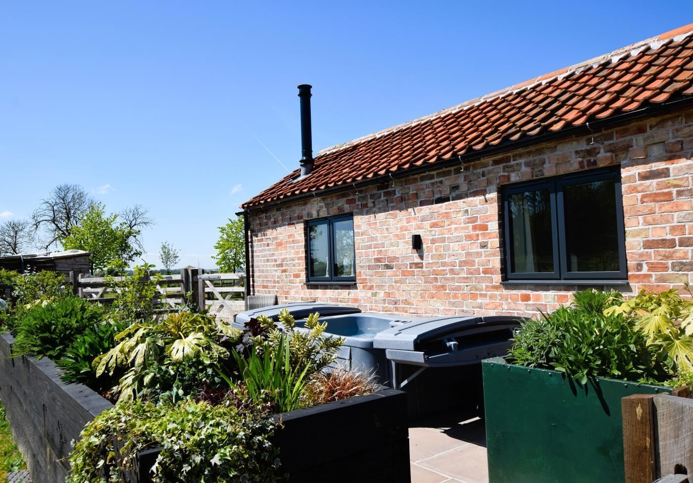A brick house with a tiled roof, a chimney, and a swimming pool.