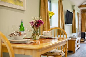 Une table à manger dressée avec des assiettes, des verres, une bouteille et un vase de fleurs.
