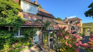 A traditional brick house with a garden, a wooden pergola, and a pathway leading to the entrance. - 5 Bed in Sedlescombe (oc-c30096) (Sedlescombe)