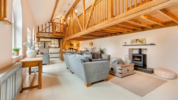 A spacious living room with a fireplace, wooden beams, and a cozy seating area. - 5 Bed in Sedlescombe (oc-c30096) (Sedlescombe)