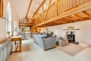 A spacious living room with a fireplace, wooden beams, and a cozy seating area. - 5 Bed in Sedlescombe (oc-c30096) (Sedlescombe)