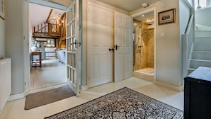 A hallway with a patterned rug, a wooden staircase, and a shower room. - 5 Bed in Sedlescombe (oc-c30096) (Sedlescombe)