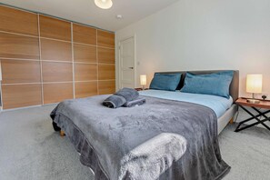 Une chambre à coucher avec un lit, une armoire en bois, une table de chevet et une lampe.