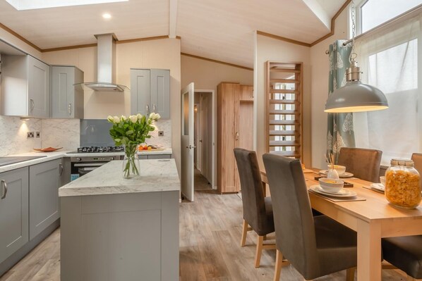 A modern kitchen with grey cabinets, a marble countertop, and a vase of white flowers. - 2 Bed in Welney (oc-c30124) (Welney)