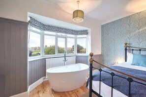 A bedroom with a large window, a bathtub, and a bed with a headboard. - 5 Bed in Whitby (oc-b30092) (Whitby)