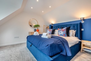 A bedroom with a large bed, a bedside table, a nightstand, a mirror, a potted plant, and a ceiling light fixture. - 4 Bed in Carbis Bay (oc-r30048) (Carbis Bay)