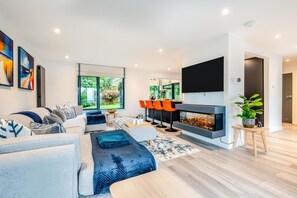 A modern living room with a fireplace, a large TV, and a sofa with throw pillows. - 4 Bed in Carbis Bay (oc-r30048) (Carbis Bay)