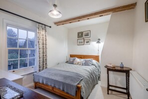 Une chambre à coucher avec un lit, une fenêtre, une table de chevet et une lampe.