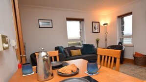 Un salón acogedor con una mesa de madera dispuesta para el desayuno, un sofá y vistas al exterior.