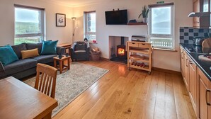 Una sala de estar acogedora con sofá, chimenea, televisor y vistas al exterior.