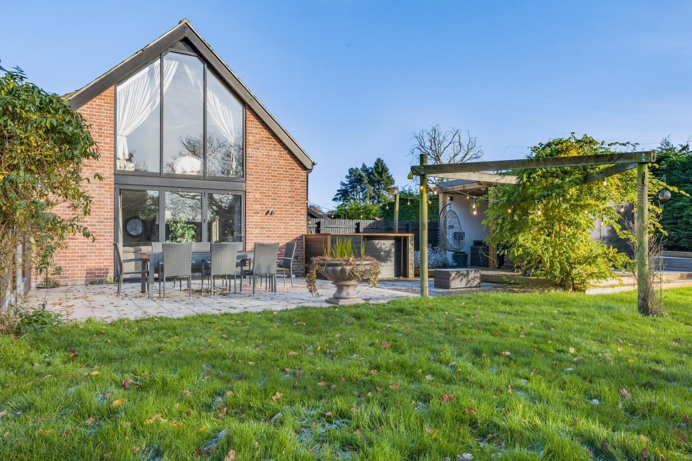 Een modern huis met een terras, een pergola en een tuin.