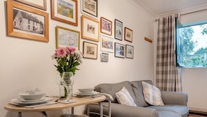Un comedor con una mesa dispuesta para dos personas, un sofá y una pared decorada con cuadros.