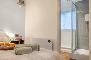 A bedroom with a bed, bedside table, lamp, and a view of a balcony with a window. - 1 Bed in Ningwood (oc-n30157) (Ningwood)