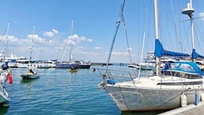 Un puerto deportivo con varias embarcaciones amarradas, un cielo azul despejado y agua tranquila.