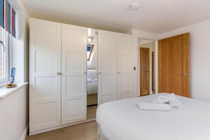 Ein Schlafzimmer mit einem Bett, einem weißen Wandschrank und einer Holztür.