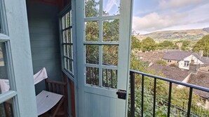 A room with a view of a village, a wooden bench, and a table with a white tablecloth. - 2 Bed in Castleton (oc-o30120) (Castleton)
