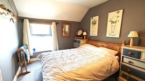 A bedroom with a large bed, a dresser, a nightstand, a window with curtains, and two wall-mounted pictures. - 2 Bed in Castleton (oc-o30120) (Castleton)