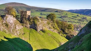 A castle on a grassy hill with a valley in the background. - 2 Bed in Castleton (oc-o30120) (Castleton)