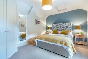 A bedroom with a bed, bedside tables, a mirror, and a wardrobe. - 2 Bed in Aldbrough St. John (oc-l30130) (Aldbrough Saint John)