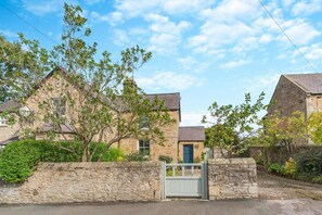 A stone house with a traditional design, featuring a stone wall and a wooden gate. - 2 Bed in Aldbrough St. John (oc-l30130) (Aldbrough Saint John)
