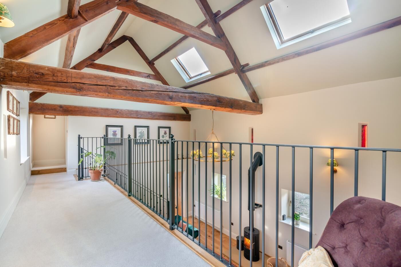 Un loft spacieux avec des poutres apparentes, un balcon doté d’une balustrade et une vue sur l’extérieur.