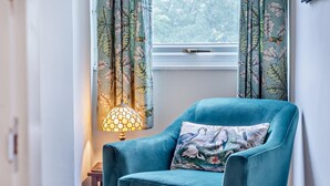 A teal armchair with a floral pillow, positioned near a window with floral curtains. - 3 Bed in Lea Bridge (oc-l30112) (High Peak Junction)