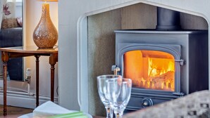 A cozy room with a wood-burning stove, a vase, and a glass of water on a table. - 3 Bed in Lea Bridge (oc-l30112) (High Peak Junction)