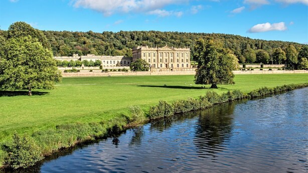 A large, historic building with a symmetrical facade, surrounded by a well-maintained lawn and a calm river. - 3 Bed in Lea Bridge (oc-l30112) (High Peak Junction)