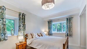 A bedroom with a large bed, wooden headboard, a nightstand with a lamp, and a window with curtains. - 3 Bed in Lea Bridge (oc-l30112) (High Peak Junction)