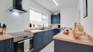 Cozinha moderna com ilha central, forno embutido e janela que proporciona luz natural.