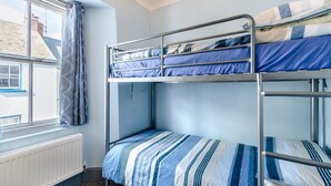 Ein Schlafsaalzimmer mit Etagenbetten, einem Fenster mit Vorhängen und einem Heizkörper.