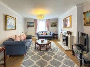 A living room with a sofa, a coffee table, a fireplace, and a television. - 4 Bed in Tenby (oc-s30142) (Tenby)