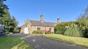 A stone house with a gravel driveway, a front garden with flowers, and a bench. - 2 Bed in Cresswell (oc-c30144) (Cresswell)