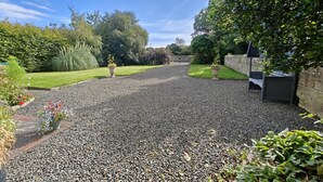 A gravel driveway leading to a house with a stone wall and a barbecue area. - 2 Bed in Cresswell (oc-c30144) (Cresswell)