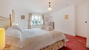 A bedroom with a large bed, a bedside table, a window with curtains, a radiator, and a door. - 2 Bed in Cresswell (oc-c30144) (Cresswell)