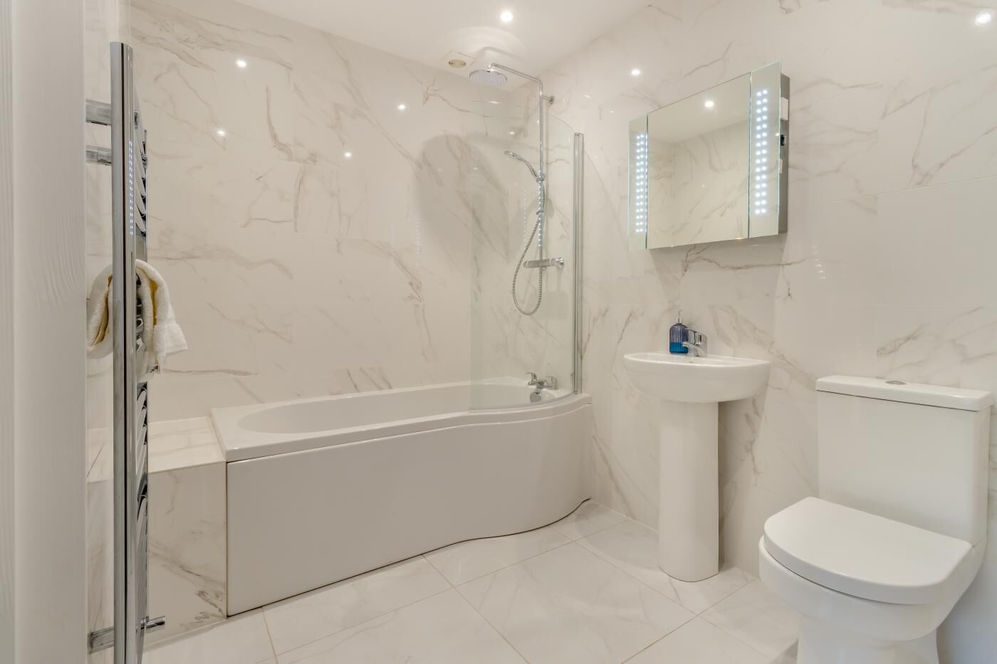 A modern bathroom with a freestanding bathtub, a pedestal sink, and a toilet.