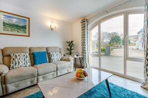 A living room with a sofa, a coffee table, and a large window with curtains. - 2 Bed in Capel Bangor (oc-m30146) (Capel Bangor)