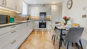 A modern kitchen with white cabinets, a built-in oven, and a dining area with a table and chairs. - 2 Bed in Capel Bangor (oc-m30146) (Capel Bangor)