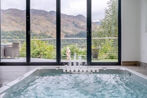 A spa area with a hot tub and a view of a mountainous landscape through large windows. - 5 Bed in St. Fillans (oc-t30058) (Saint Fillans)