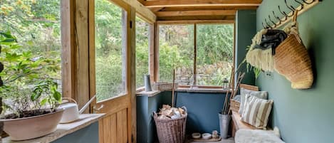 A rustic wooden room with a large window, a wall-mounted rack, and a cozy seating area.