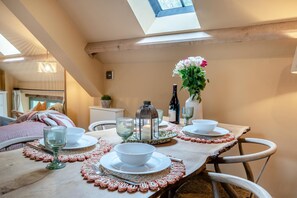A dining area with a table set for two, featuring a candle, wine bottle, and a vase with flowers. - 2 Bed in Cwmdu (oc-l30162) (Cwmdu)