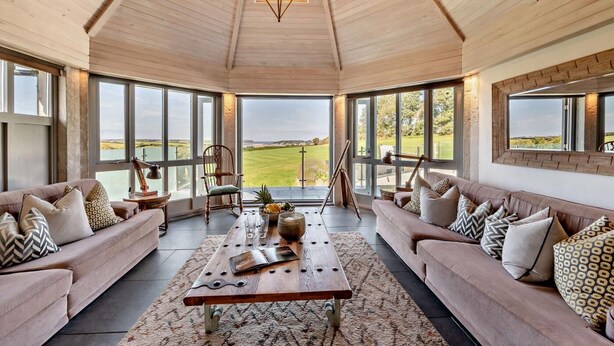 A spacious room with a high ceiling, large windows, and a view of a golf course. - 5 Bed in St. Issey (oc-r4328) (Saint Issey)